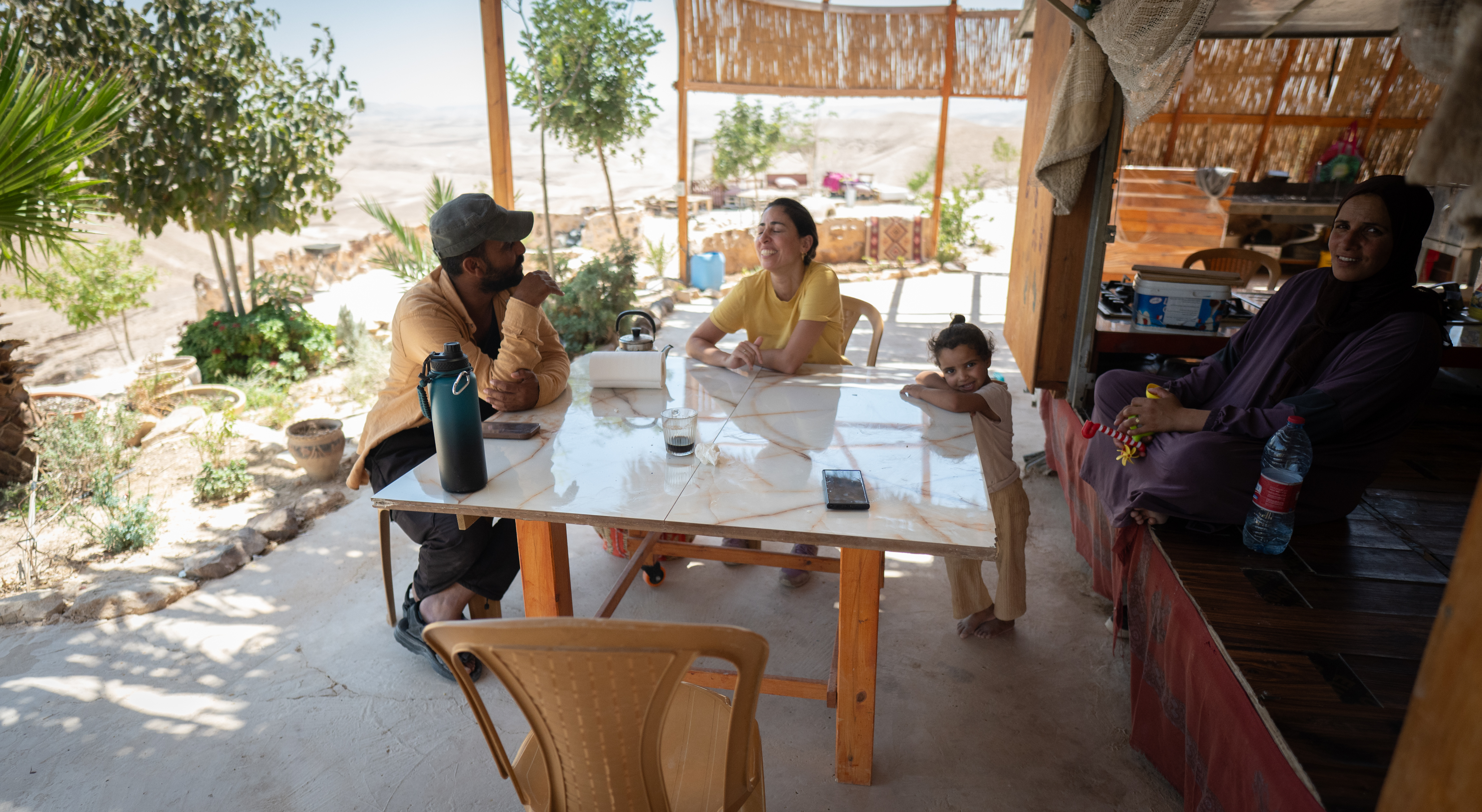 People gathered around a shaded outdoor table at the camp