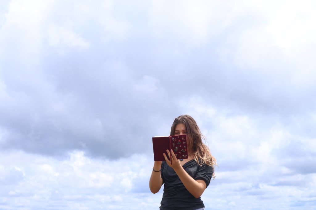 A writer holding a red notebook outdoors